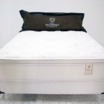 A white bed with black pillow and mattress