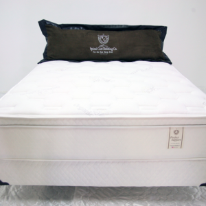 A white bed with black pillow and mattress