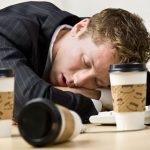 A man is sleeping on the table with coffee.